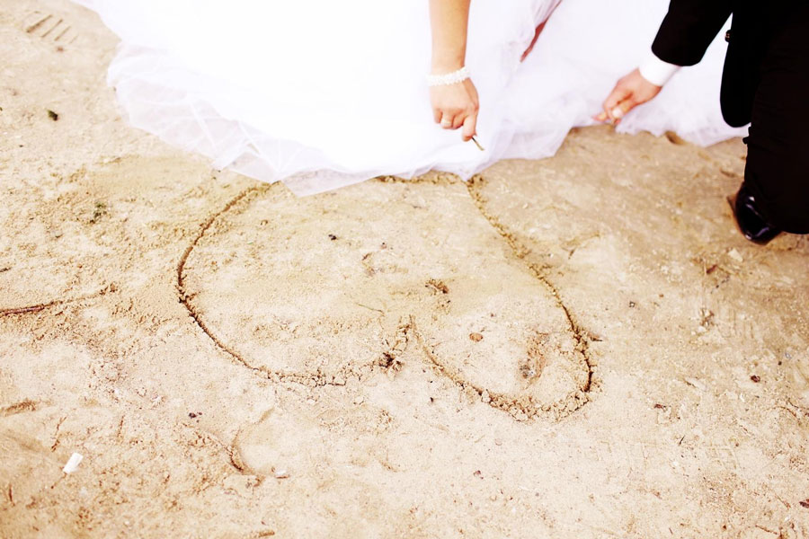 Brautpaar zeichnet Herz in den Sand